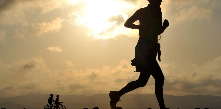 woman running with children on bikes in background infront of mountains 